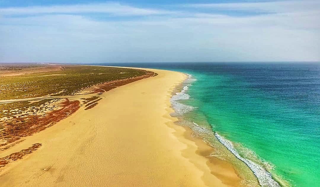Veduta aerea di una lunga spiaggia dorata tra le dune e l'oceano turchese di Boa Vista