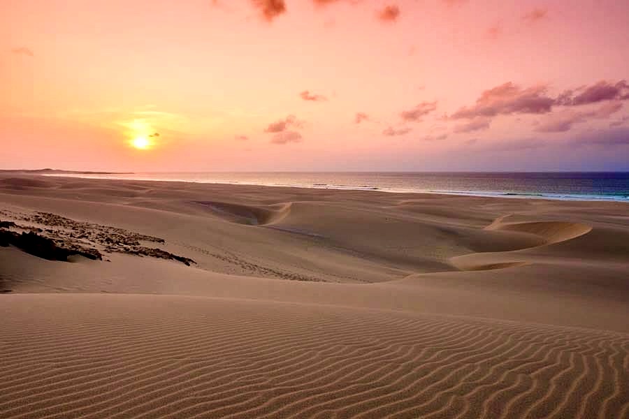 Dune di sabbia al tramonto sotto un cielo rosa e arancio, a Boa Vista
