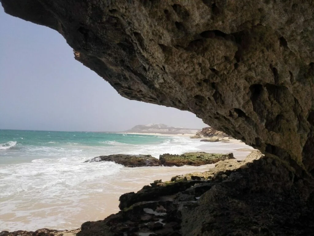 Grotta scavata dal mare nella roccia scura a Praia da Varandinha