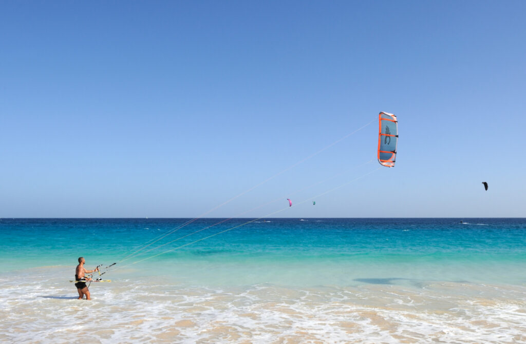 Un kitesurfer prepara la vela sull'acqua turchese di Capo Verde