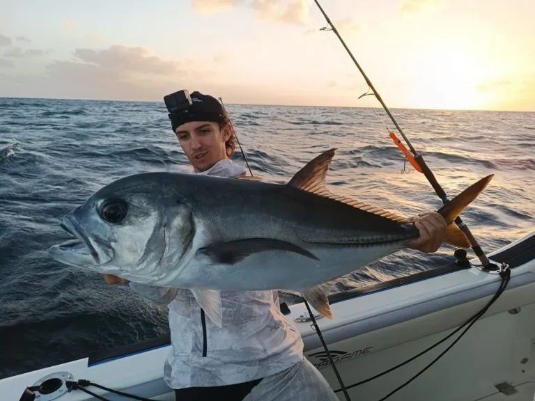 Pescatore in barca al tramonto con un grosso carangide