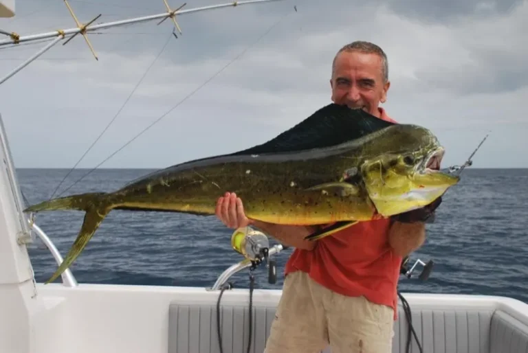 Pescatore sorridente con una lampuga dai colori giallo e verde