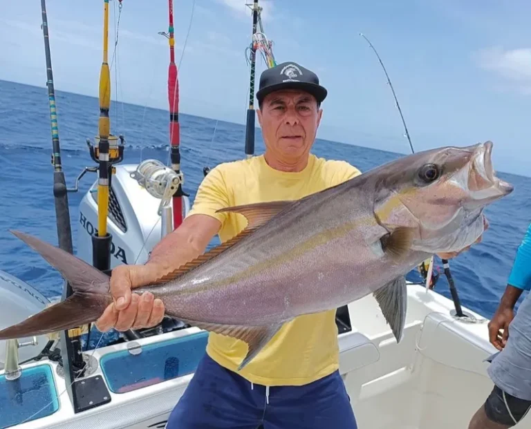 Pescatore con una ricciola a bordo, canne sullo sfondo