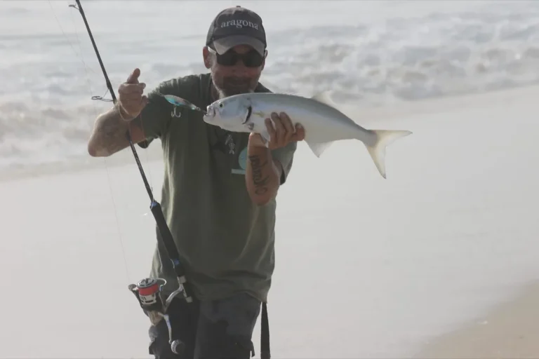 Pescatore sulla spiaggia con un pesce serra