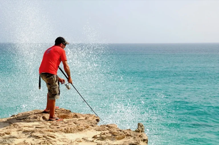 Pescatore sulla roccia davanti al mare turchese