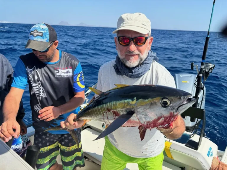 Due pescatori a bordo con un tonno pinna gialla appena salpato