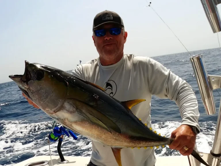 Pescatore a poppa con un tonno pinna gialla