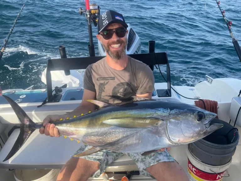 Pescatore seduto a poppa con un tonno pinna gialla