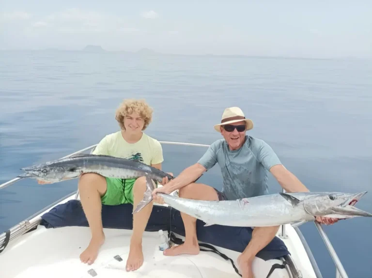 Padre e figlio seduti a prua con due wahoo